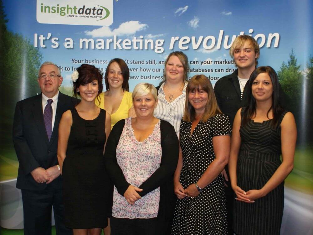 Insight Data team posing in front of a promotional backdrop during a 2010 marketing campaign.