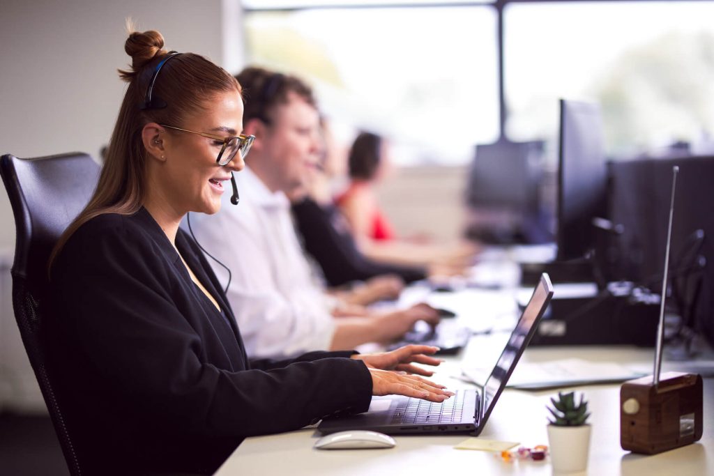 Elle from Insight Data wearing a headset, working on a laptop in a professional call centre environment, assisting clients with lead generation and customer support.