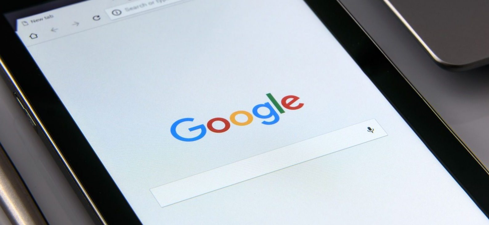 Google Search homepage displayed on a tablet screen with visible voice search icon.